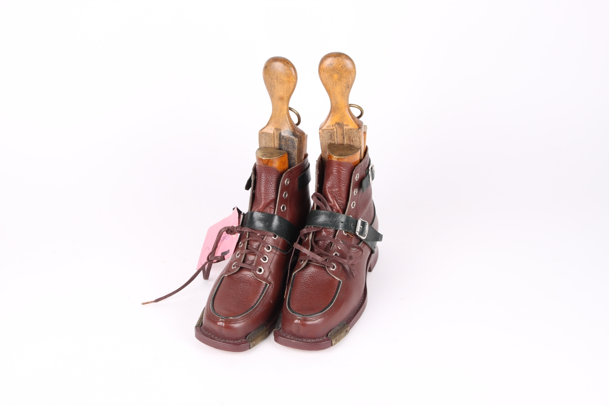 Et par beksømstøvler i lær med maljer og snøring foran, samt stramme-remmer over vrist og ankel. Støvlene har trelester inne i skoene.