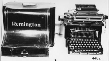 Skrivmaskin av märket Remington. Amerikanskt fabrikat från slutet av 1800-talet. Den är svartlackerad med gula ränder. Tangenterna är vita och försedda med glas.
Märkt i taggad röd stämpel med gult: To Save Time Is To Lengthen Life. Standard Trade Mark Remington Typewriter.
Framtill på stommen märkt i gult: Remington Standard Manufactured By Wyckoff Seamans och Benedict Ilion New York USA.