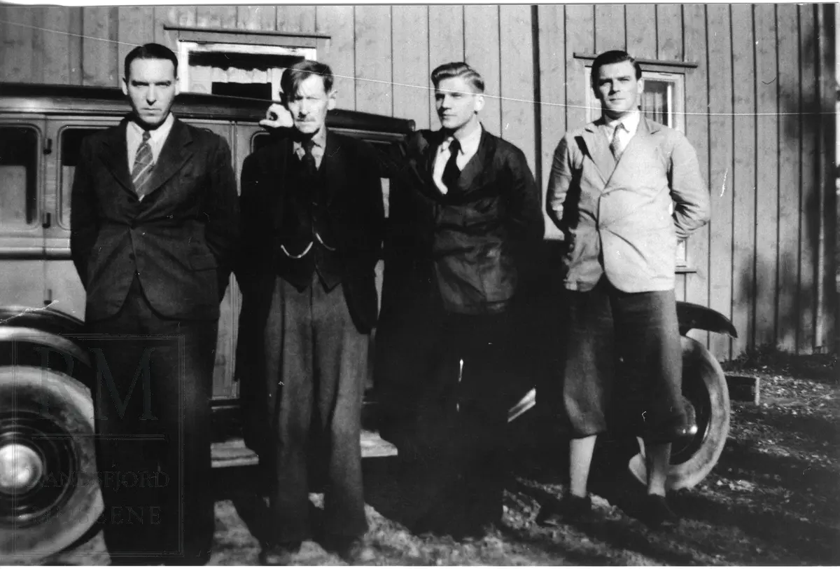 Fire herrer står oppstilt foran en bil.