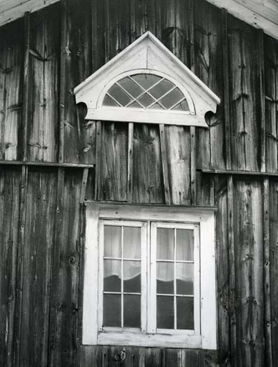 En byggnad med två fönster varav ett lunettfönster vid Bortomåa i Fågelsjö.