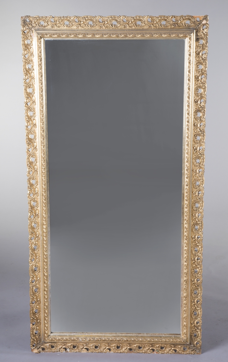 Rektangulært speil med forgylt ramme. Opphøyd rammekant inntil speilet, med asymmterisk ornament rundt dette. Støpt ornament som er limt på treverk.