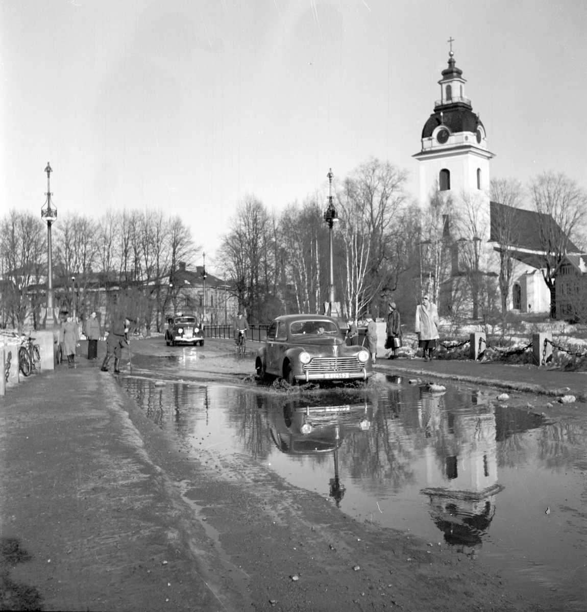Vårreportage. Bil på Drottningbron, Heliga Trefaldighetskyrkan, översvämning. Den 3 mars 1950