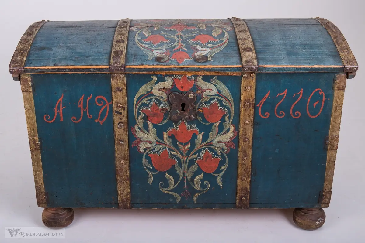 Rosemaling på blå bunn.  Det midtre feltet er dekorert med symetrisk rosemaling på blå bunn . I de to andre feltene på fronten er malt med initialene.