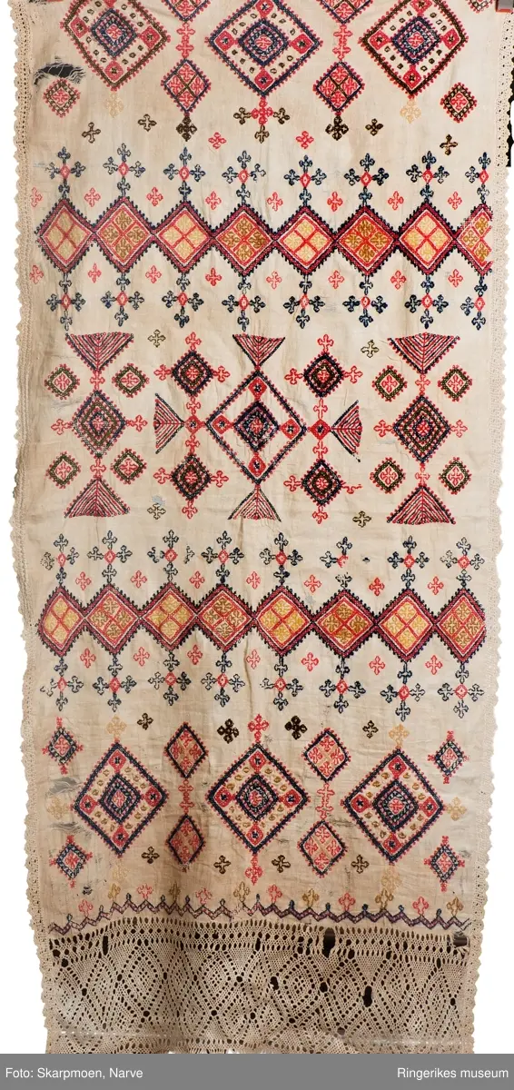 Kvadrater stilt på høykant, små kors og 8 armete staker? Motivene er stilt i rader over hele duken. Gjenombrutt bord med kvadrater i en kortende