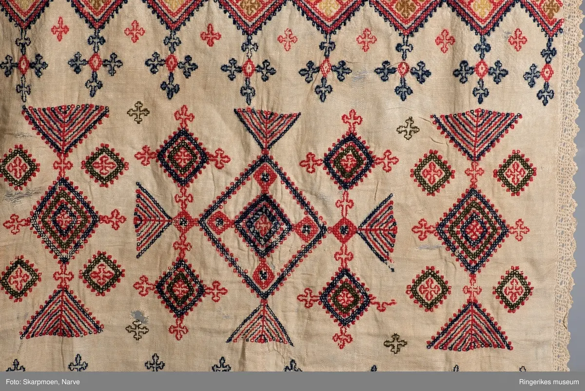 Kvadrater stilt på høykant, små kors og 8 armete staker? Motivene er stilt i rader over hele duken. Gjenombrutt bord med kvadrater i en kortende