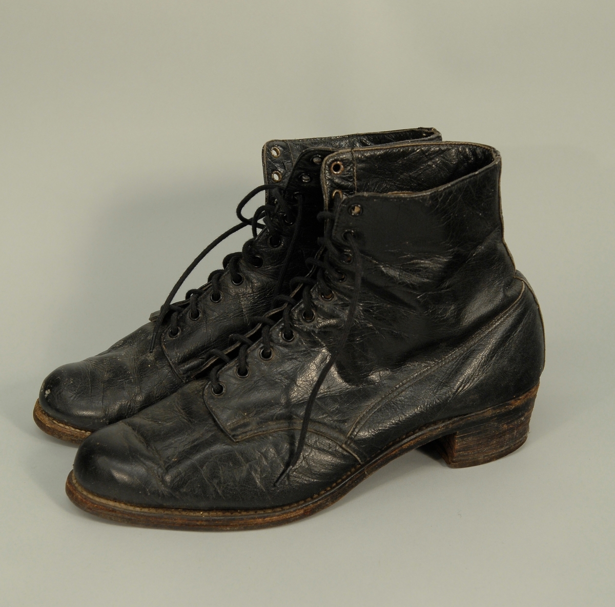 Skoene går opp til vristen, har snøring med 2x10 hull, av svart lær, og har ein liten flat hæl. Foret med hvitt bomullsstoff. Str. ca. 39.
