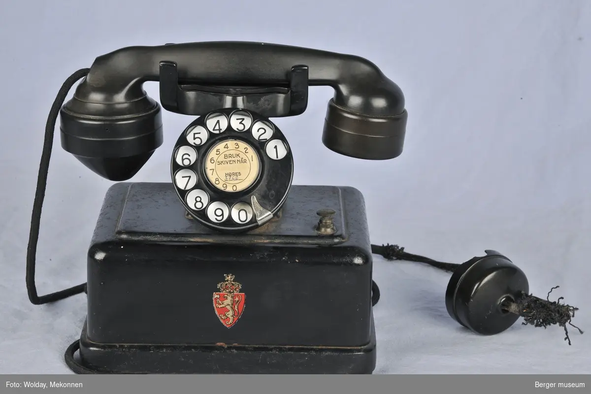 Telefonen har vanlig tallskive i motsetning til tallskiven i Oslo som hadde 9 der denne har 1 osv. Riksvåpenet er på forsiden av telefonen.