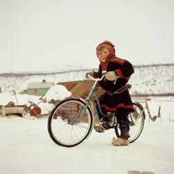 En gutt kledd i tradisjonell samedrakt poserer med sykkel.