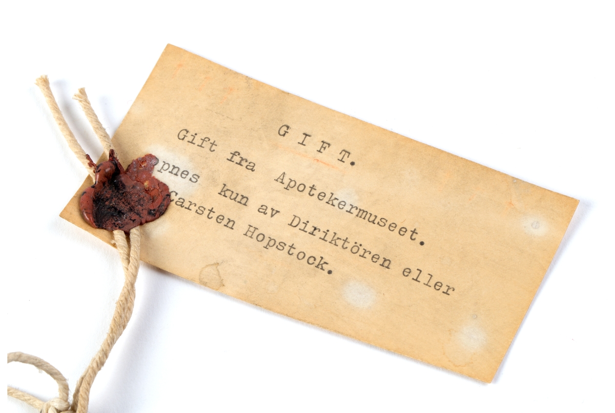 Skrin med hengslet lokk og innhold:
64 glassrør med kork påført nummer fra 1 til 64. Numrene korresponderer med plakat festet i lokket der virkestoffenes navn fremkommer. Påført nummer og navn også på hvert glassrør.