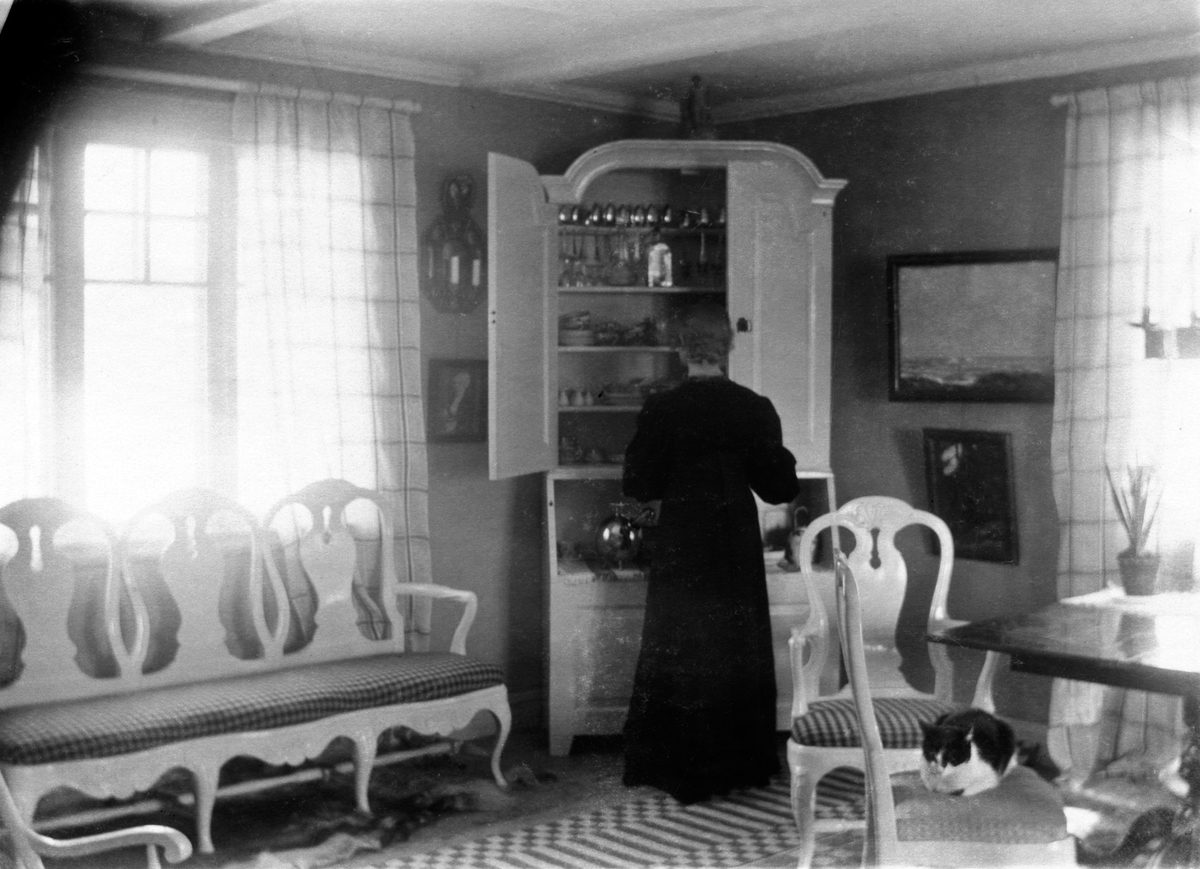 Ester Ellqvist-Bauer står i ett rum i stugan de hyrde i Torstorp utanför Gränna och tittar in i ett skåp med glas och porslin.