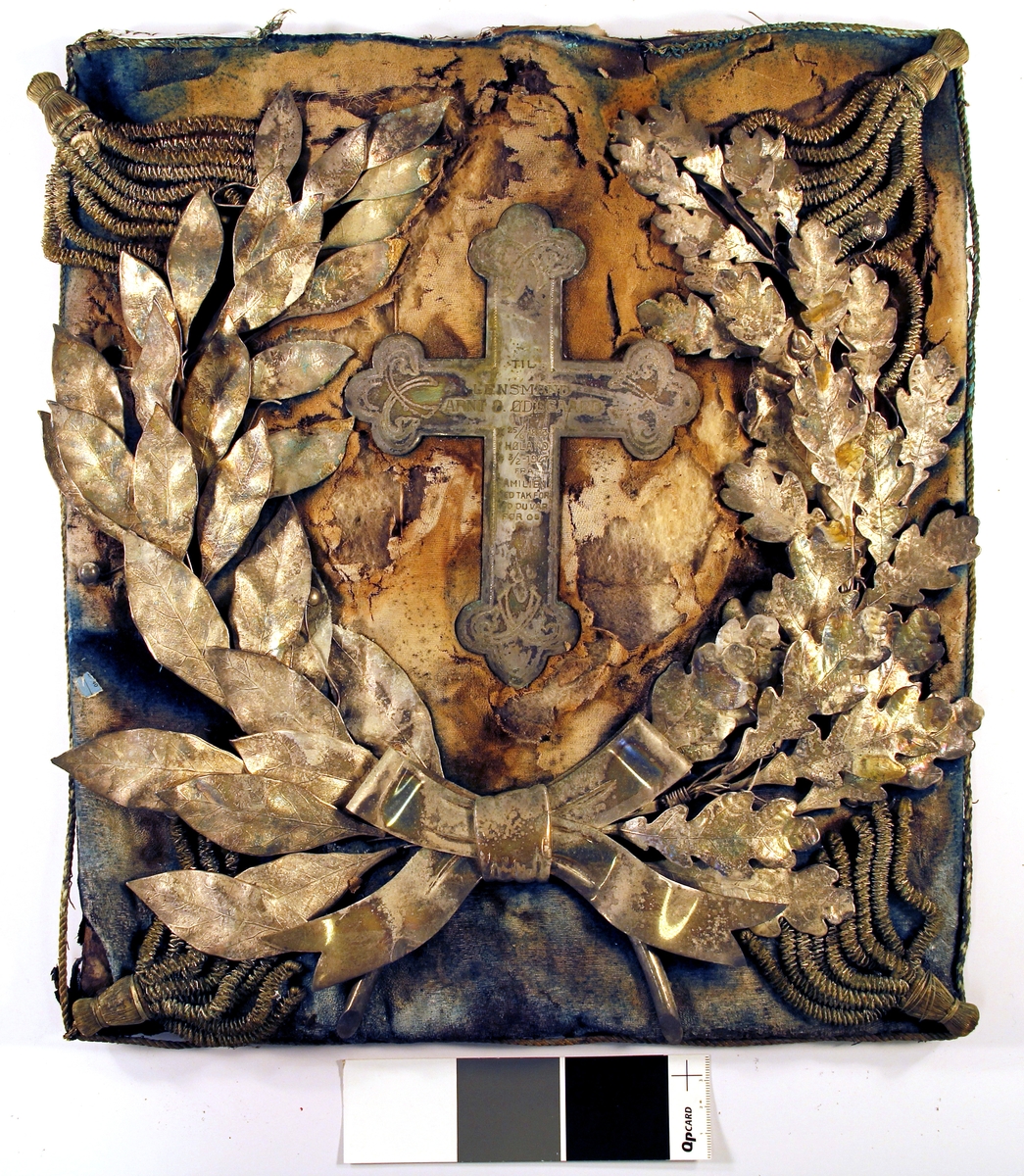 Kors omgitt av krans av blader i relieff.