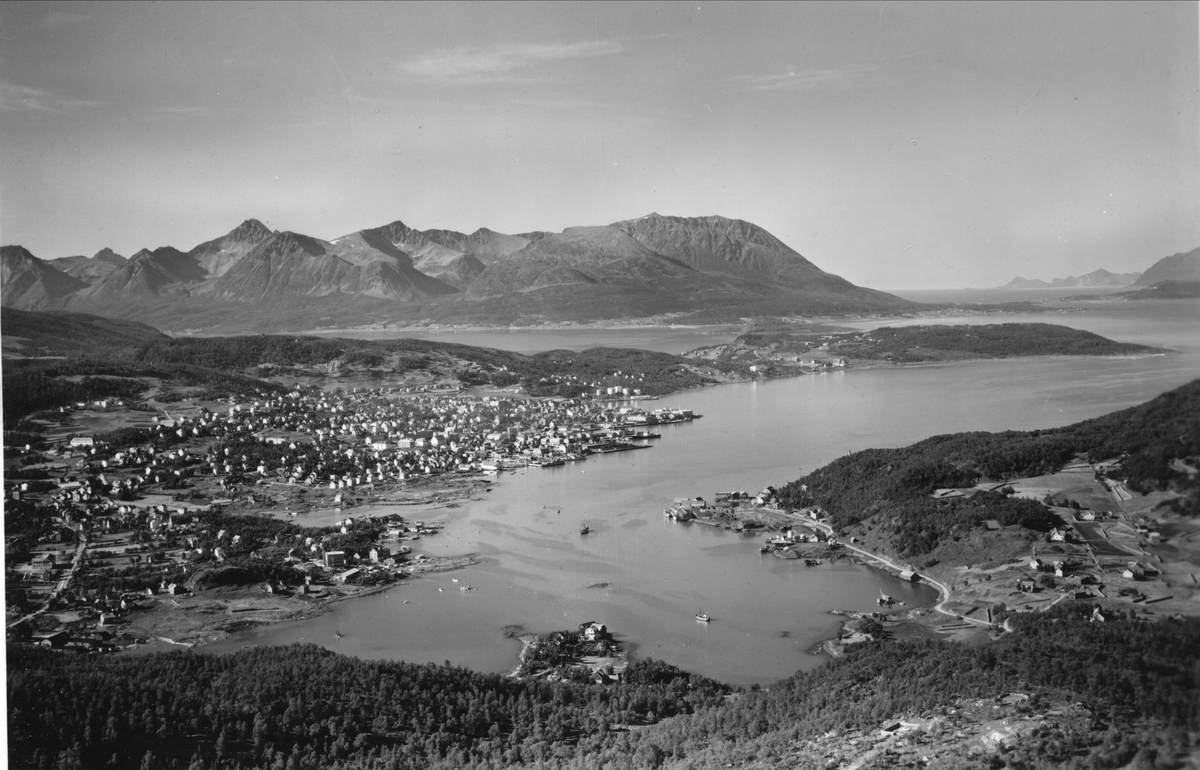 Flyfoto fra Harstadbotn og Gangsås, med byen i mellomgrunnen og Grytøya bakerst. Restene av tysk luftvernstilling i forgrunnen.