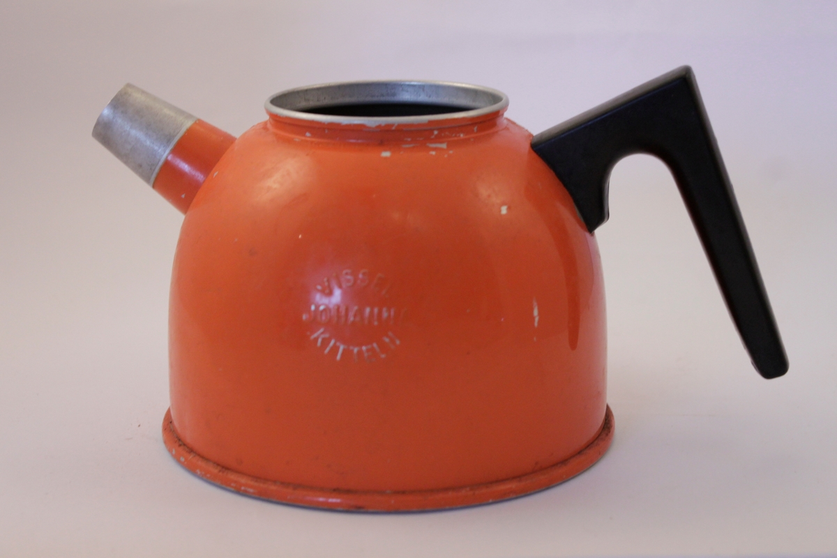 Orange kaffepanna i plåt som saknar lock samt plastplopp att placera på pipen för att visselfunktionen ska fungera. Pannan "visslar" när kaffet eller vattnet kokar.