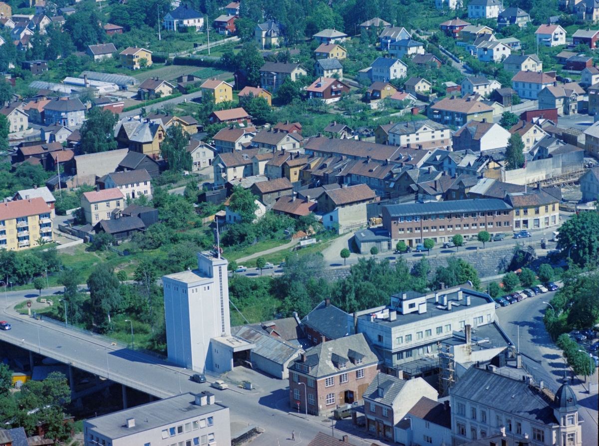 Flyfoto, Lillehammer sentrum med Kirkegata og Kirkegatebrua nærmest. På andre siden av Mesnaelva går Brubakken. Nymosvingen vises i nedre høyre hjørne med hvit stor bygning, Nymosvingen 2 sentralt. Den stor hvite bygningen er Lillehammer Mølle med kornsiloen. Larsens Pipefabrikk synes i nedre kant.