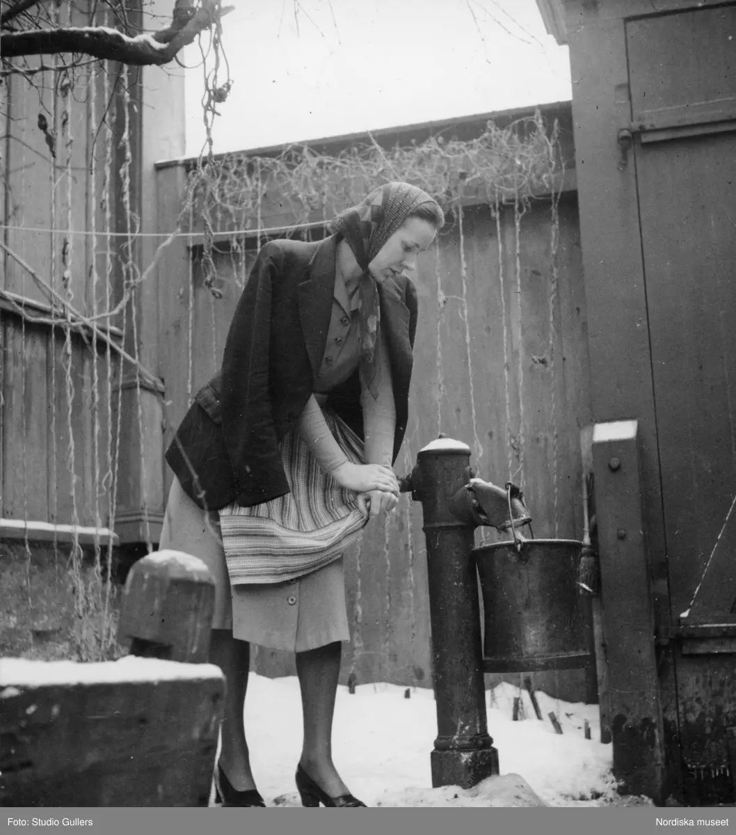 Fru Birgitta Törnqvist pumpar vatten på en bakgård på Mäster Mikaels gata 9, Södermalm, Stockholm.