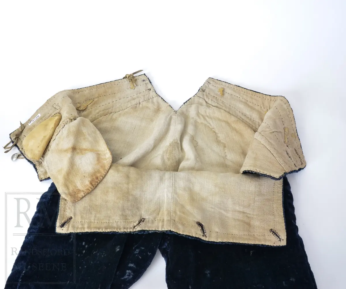 Mørk blå fløyelsbukse, knelang, med lem. Foret i lin. Fem flate messingknapper.