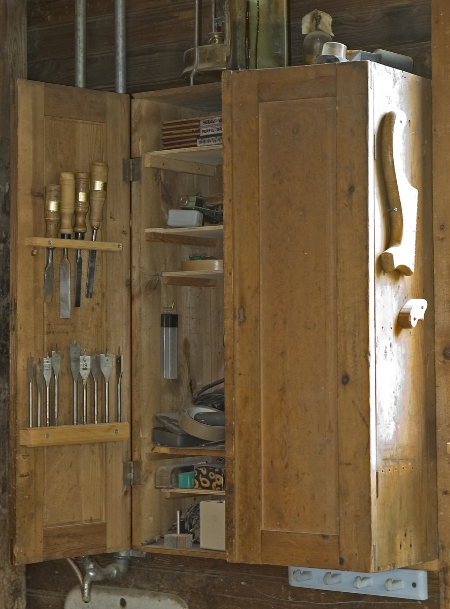 Skåp av trä för förvaring av verktyg. Verktygsskåpet har två dörrar som är tillverkad med ram och fyllning. Skåpet är omålat. På skåpet är 10 inristat på den ena dörren.

Funktion: Möbel för förvaring av verktyg