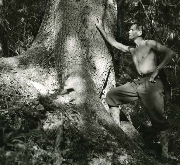Hilding står med ena handen mot barken på en grov trädstam.
