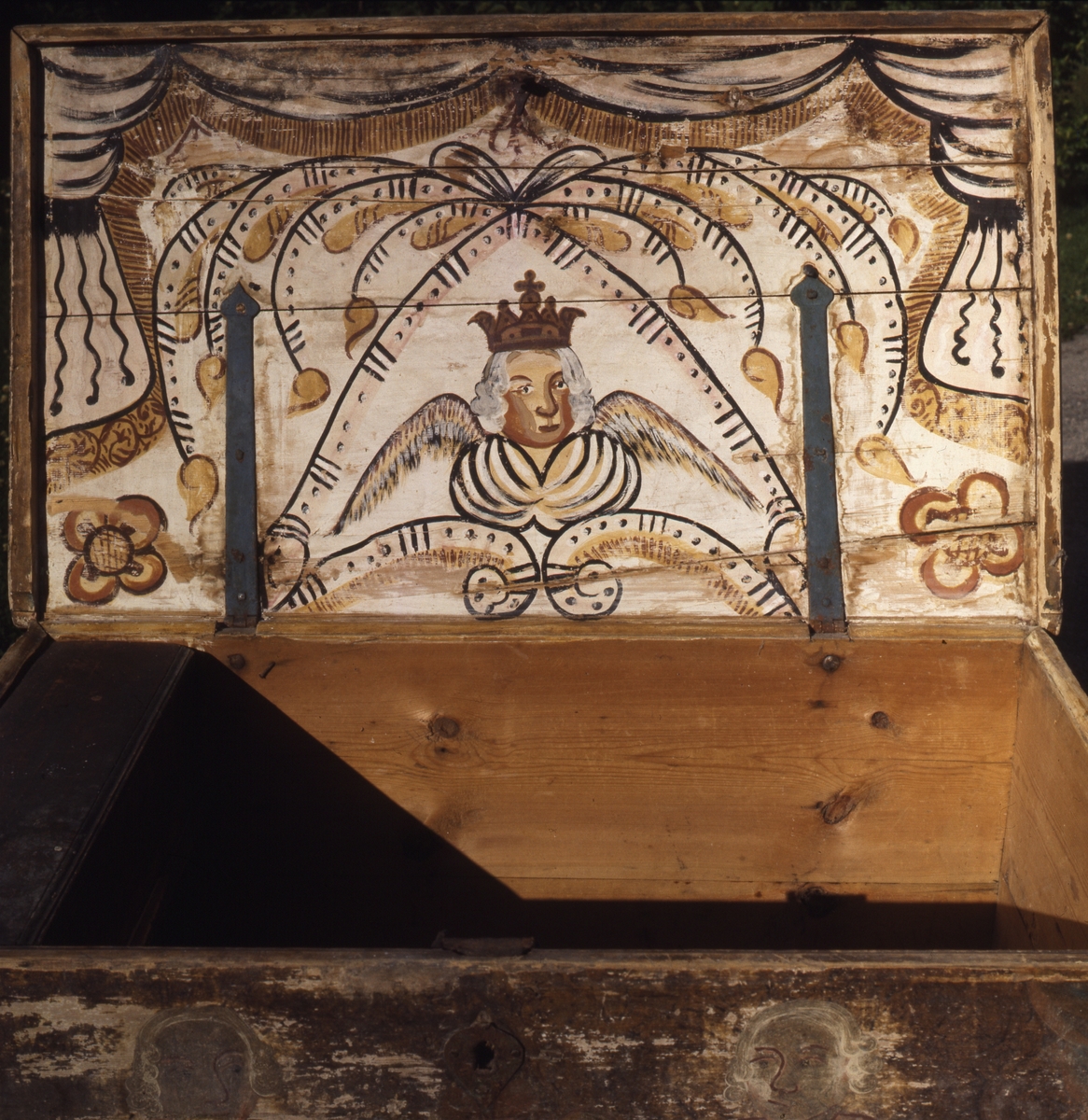 Målning på insidan av kistlock, ängel med krona.