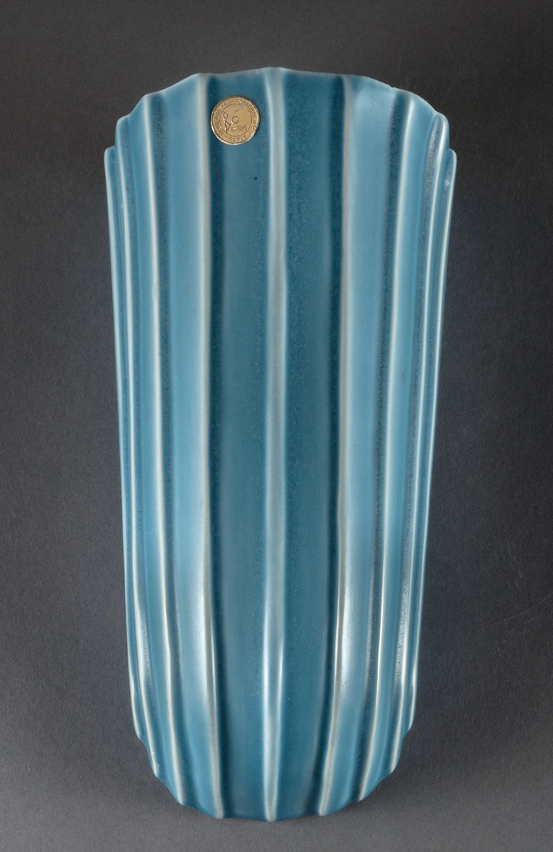 Väggvaser, 2 st, i fajans, Bobergs fajansfabrik, formgivare Ewald Dahlskog. Svagt S­svängd front med raka, uppåt något utvidgade sidor. Mönster av vertikala räfflor. Glaserade ljusblå. 
Modell: D93, 1935-53
Modell: D191 (liten), 1938-53