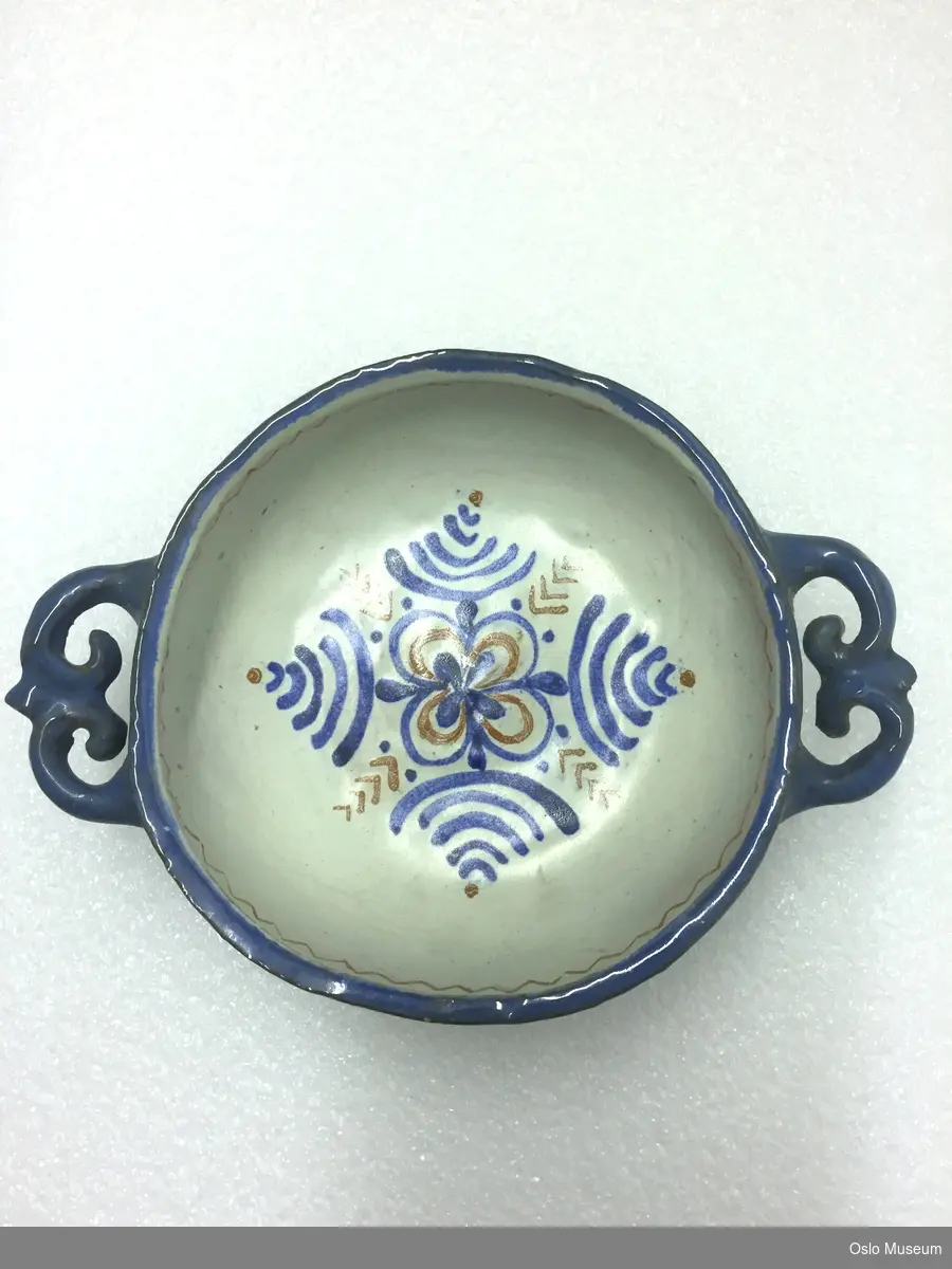 A: Mugge, B-C: 2 boller og D-K: 8 tallerkener i hvit- og blåglasert keramikk med dekor. L: Mugge