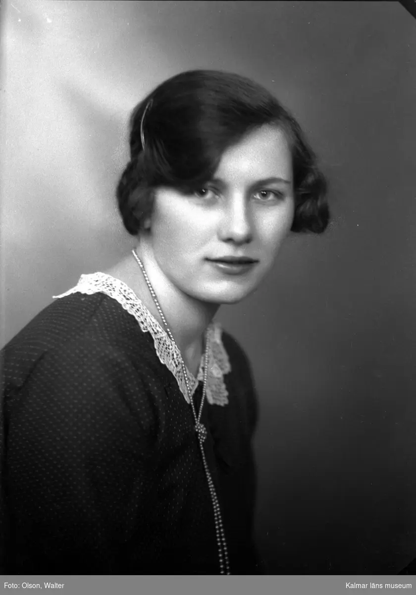 Ateljébild på en kvinna i halsband och jumper. Enligt Walter Olsons journal är bilden beställd av fröken Kerstin Schierlund.