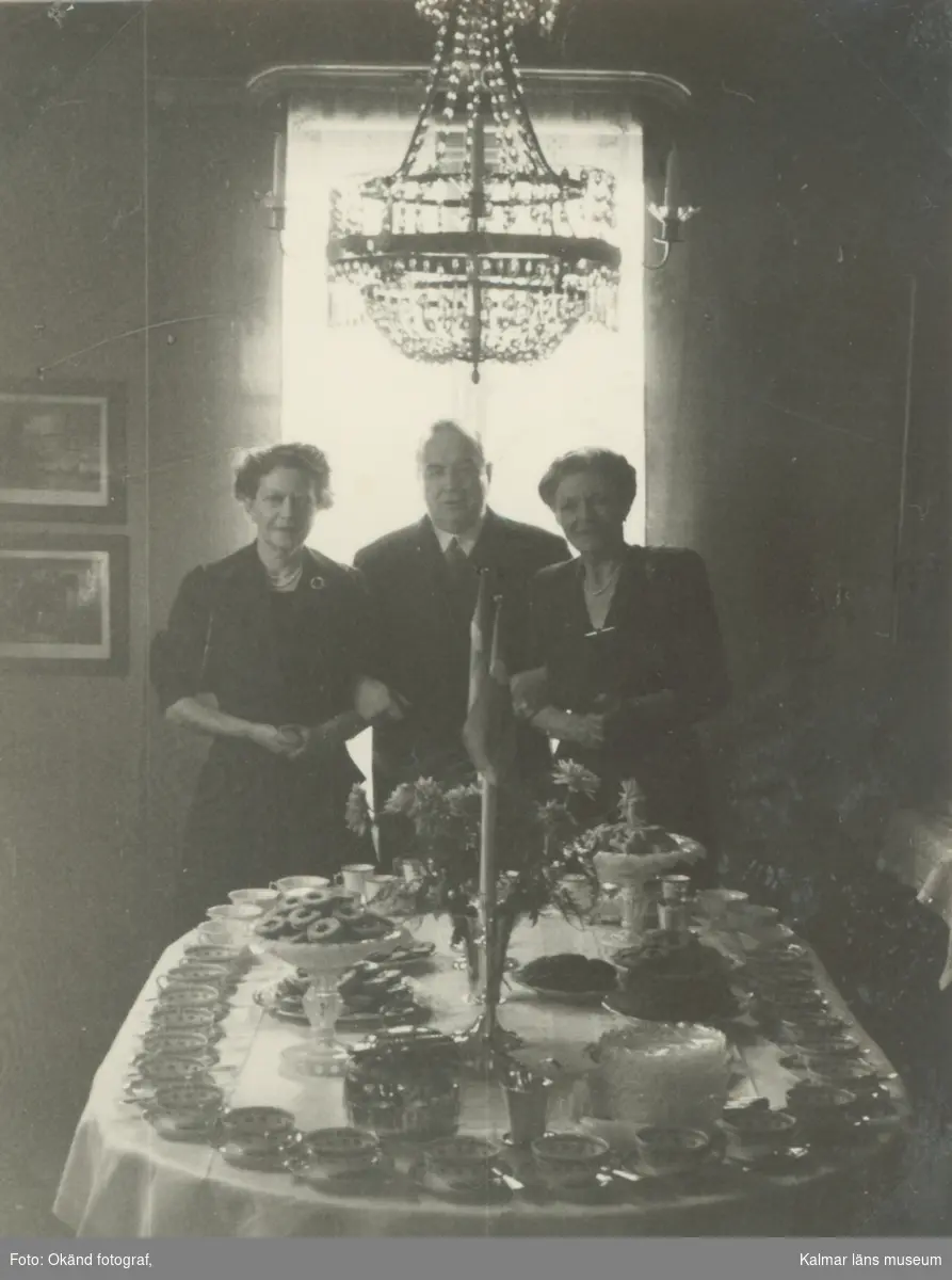 Interiörbilder från Le Grands Hem på Västerlånggatan. Systrarna le Grand och en man vid ett festbord.
