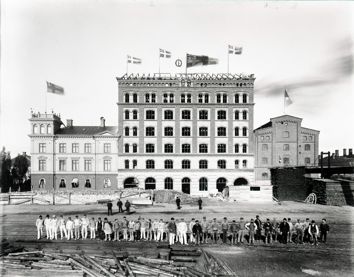 Kalmar Ångkvarn under byggnad. Taklagsfest med arbetarna uppställda framför.