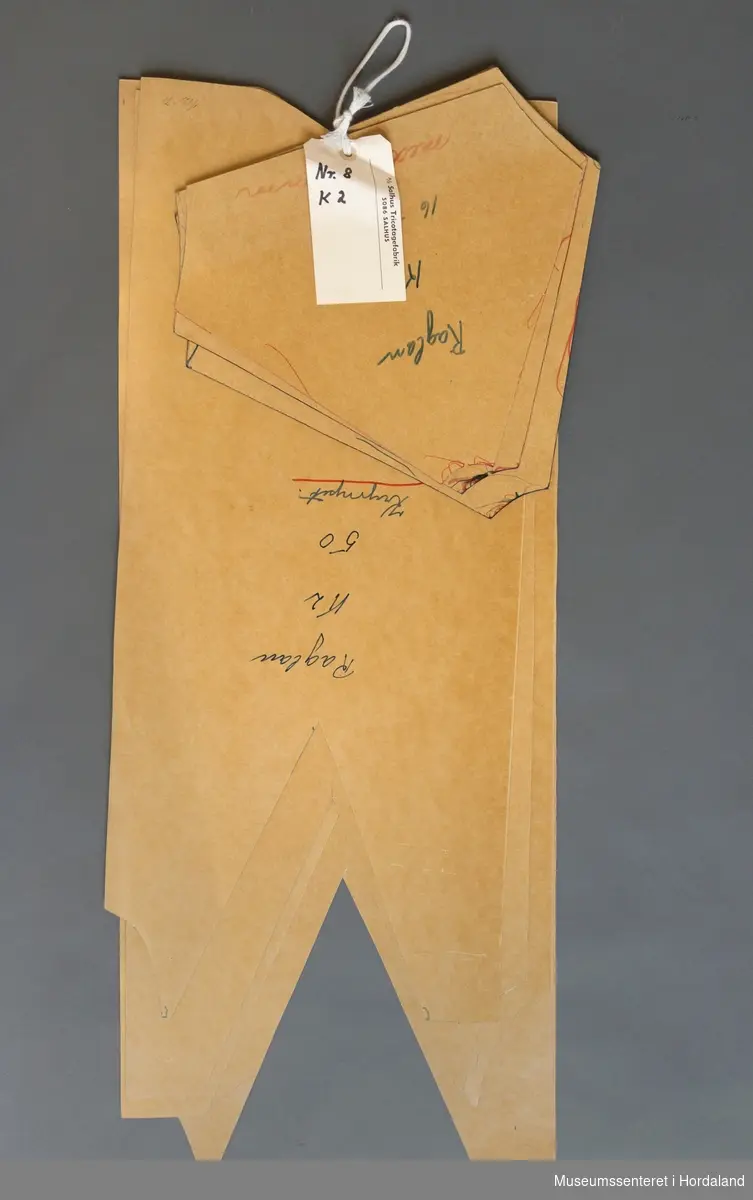 Mønsterskantar i papp, brukt til å skjere ut ulike delar av plagg i klesproduksjon. Desse er til plagg merka "raglan krympet", i kvalitet K2, nr. 8. Str. 50-56.