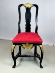 Svart stol med utskjæringer malt i gull, buede forbein og sete med lyserødt trekk. Fjærer i setet.
