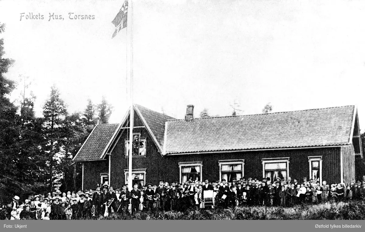 Folkets Hus i Torsnes, Borge ved Fredrikstad, ca.1910. Prospektkort. Menneskemengde og musikkorps.