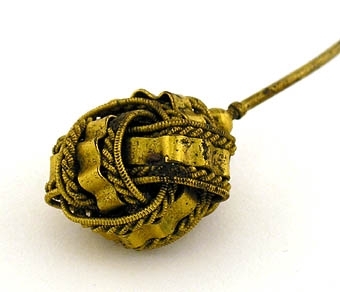 Schalnål av mässing, knappen i form av ett flätat band.