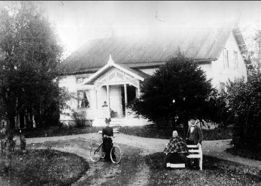 Forsvik, omkr 1895 - 96. Ingenjör Oscar Lundbergs bostad "Lundberga" kallas i dag Björkviken. På trappan sitter ingenjören vid bruket Oscar Lundberg, på bänken hans hustru Sofie och bakom står sonen Nils. Vid cykeln står dottern Ida.