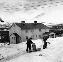 Personer, klær, kjelke, melkespann, 2-etg. bolighus.