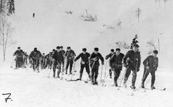 Menn, uniform, ski og skistaver, naturforhold. 
Skiløpertro