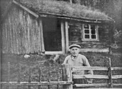 Mann, gjerde, bolighus.