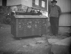 Rosemalt kiste står ute på tunet ved siden av en mann. Bil o