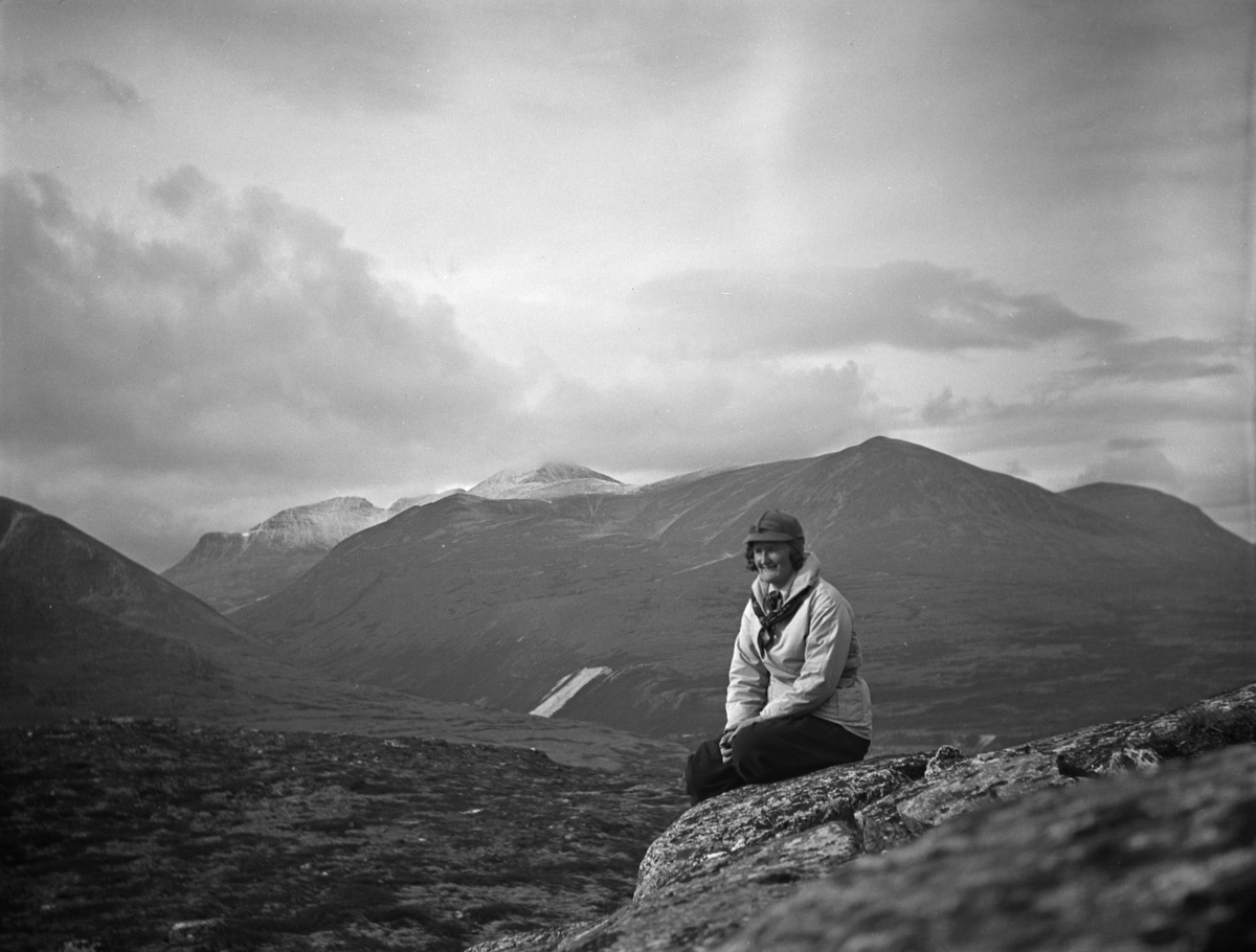 Rondane. Kvinne sitter på fjellet, antagelig på Musvolkampen. Langglupdalen inn tv., Høgronden tv. for midten av bildet.