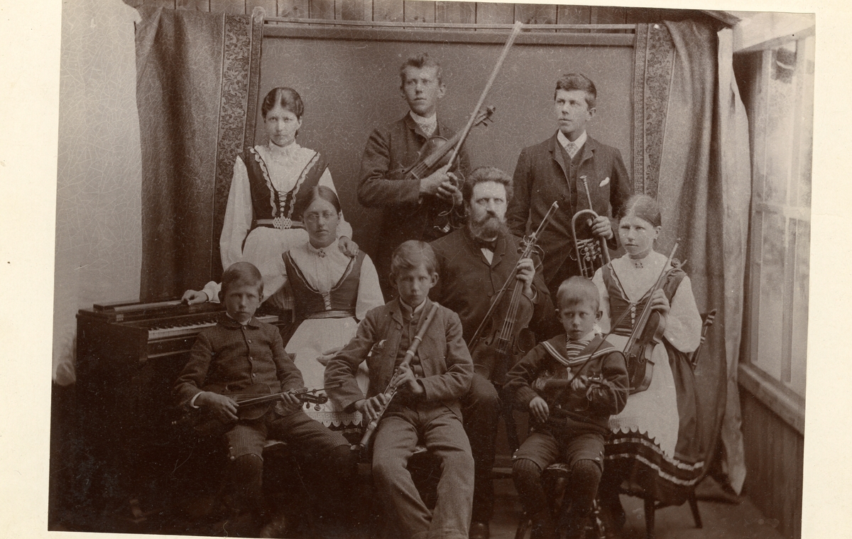 Gruppebilde av en familie med forskjellige instrumenter. De er kledd i bunad/folkedrakt og dresser.