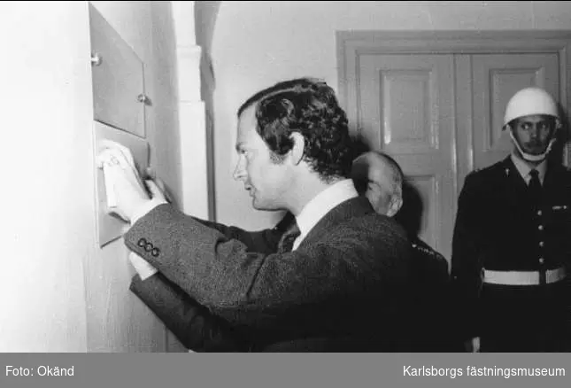 Karlsborg, Carl XVI Gustaf skriver sitt namn på plattan vid muséets entré 13/5 1975. Överste Eriksson skymtar i bakgrunden. Gåva från SLA 2003.