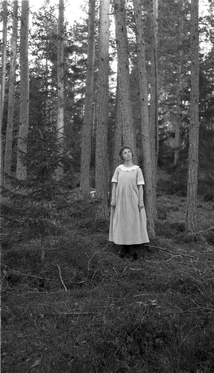 To bilder av en ung kvinne i helfigur, på det ene sittende på en stein, på det andre stående i skogsterreng. Kvinnen er trolig Dora Alice Martinsen fra Sanden søndre i Østre Toten.