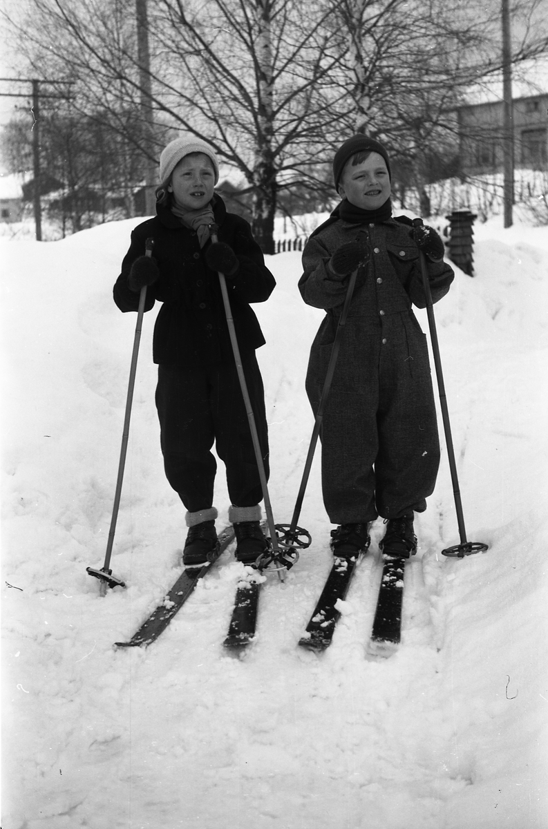 Serie på seks bilder av to uidentifisertee barn, på noen bilder på ski, på andre med spark. Stedet er gårdsplassen på Odberg på Kraby, fotografens eiendom.