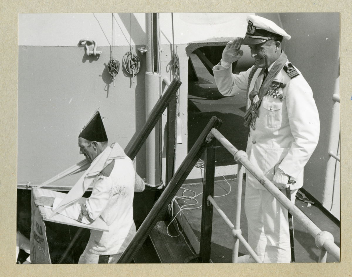 Bilden föreställer två män under ceremonierna kring ett linjedop ombord på minfartyget Älvsnabben i samband med långresan 1966-1967. Mannen till höger är fartygschefen, kommendörkapten 1. gr Lennart Lindgren. Han är klädd i långreseuniform nr 1 och gör honnör. Den andra mannen, Oskar Linde, är klädd i en utklädnad.