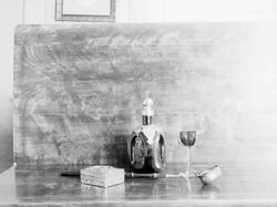 Stilleben, skjenkeflaske og glass og skrin.