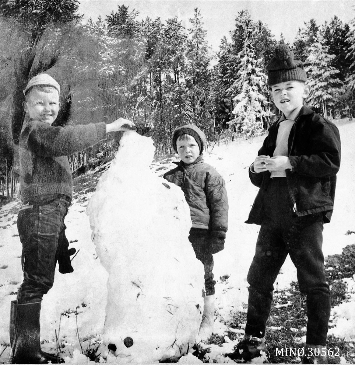 Tre barn som bygger snømann