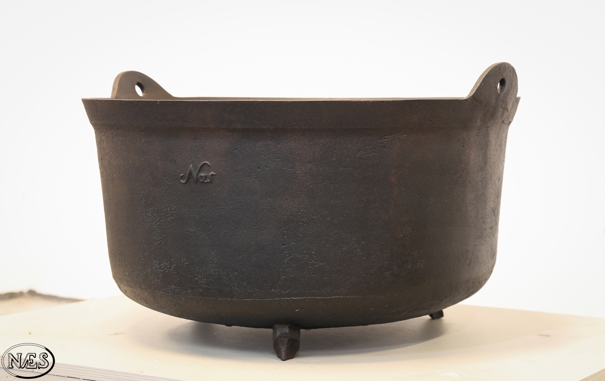 Rund jerngryte med tre bein og to ører på øvre kant for feste av hank.