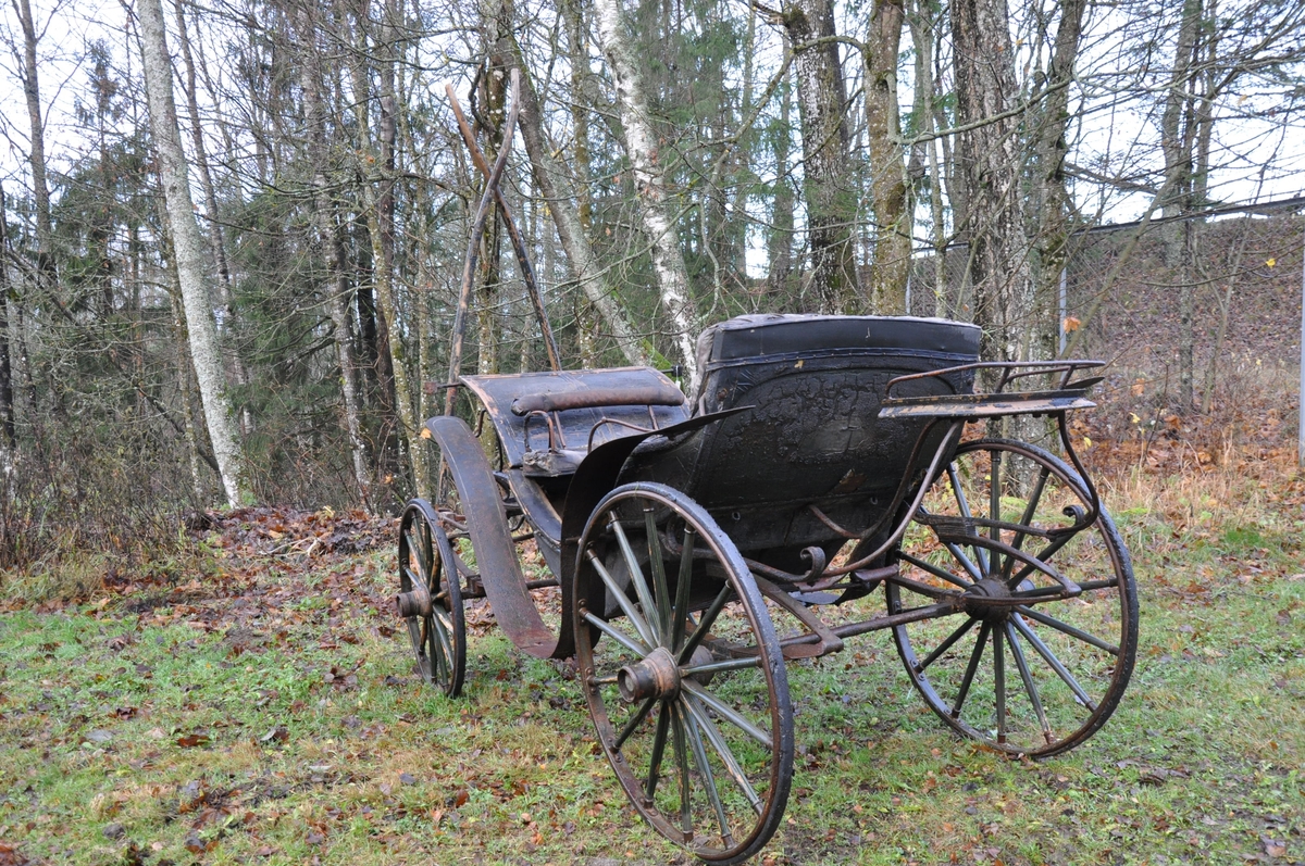 4-hjuls vogn for trekk med én hest. Trilletype. Spesielt stor fløy (skvettskjerm) . Lakeisete bakerst, stort hovedsete, lite motsete.