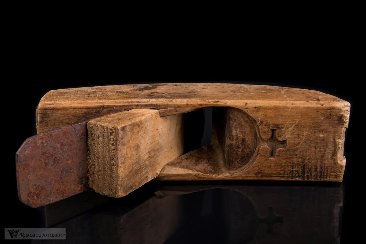 I forlengelse av sponhuset er det skåret ned i treet en halvsirkelform med et lite kors på toppen som minner om toppen på et kongelig rikseple.