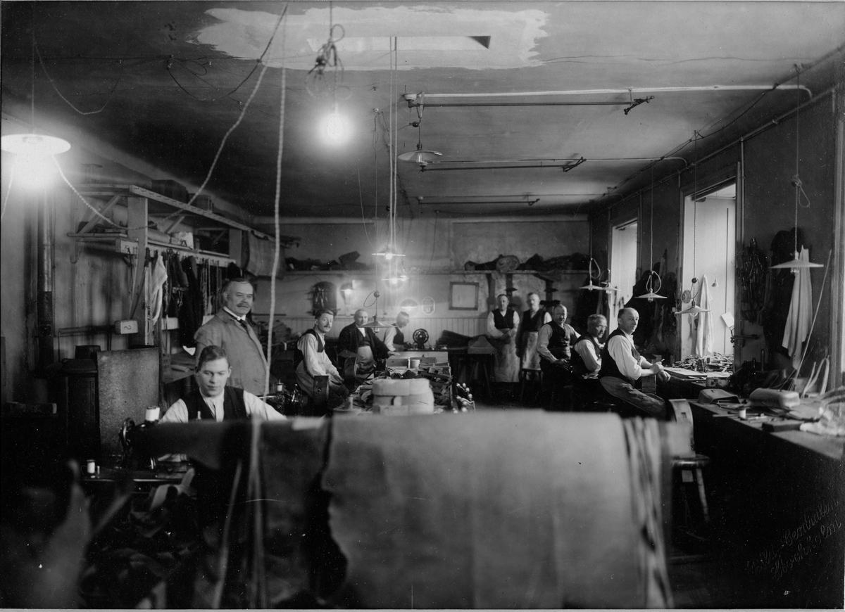 Hantverkare sitter vid arbetsbänkar i verkstad.