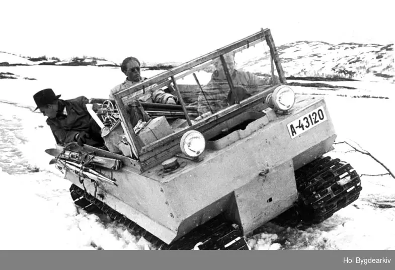 To menn på en Studebaker Weasel M29 under bygging av Holsanlegget: kraftutbygging, beltebil, på isen, menn3, sjåfør, skiutstyr.